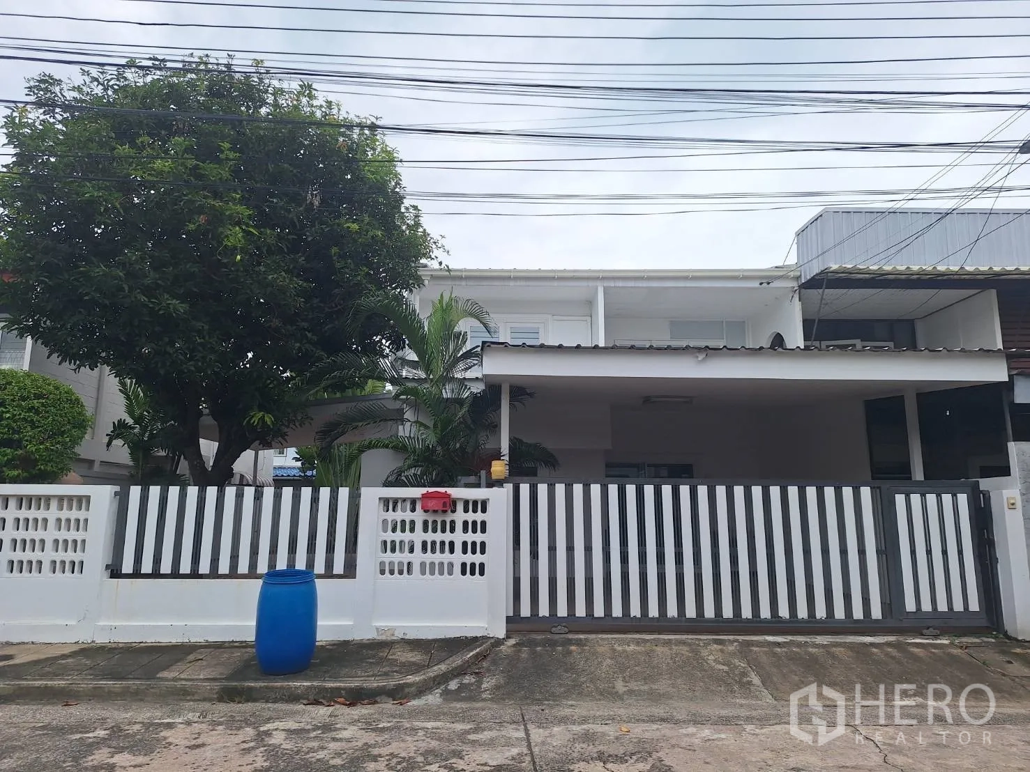 Detached House for rent in Saphan Sung, Bangkok - Street-facing white detached house with striped metal gate, covered porch, and mature trees.