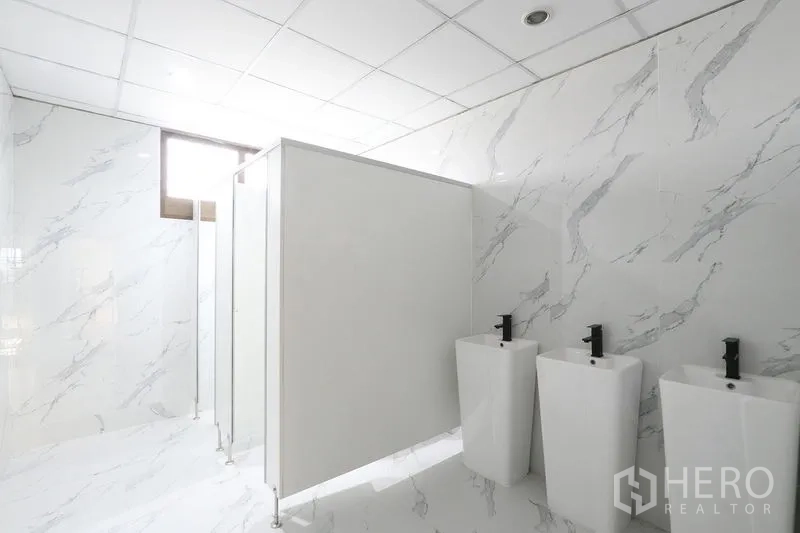办公空间 出租在Bang Na, Bangkok - 卫浴空间设三个位盆、隔断与仿大理石墙面。
