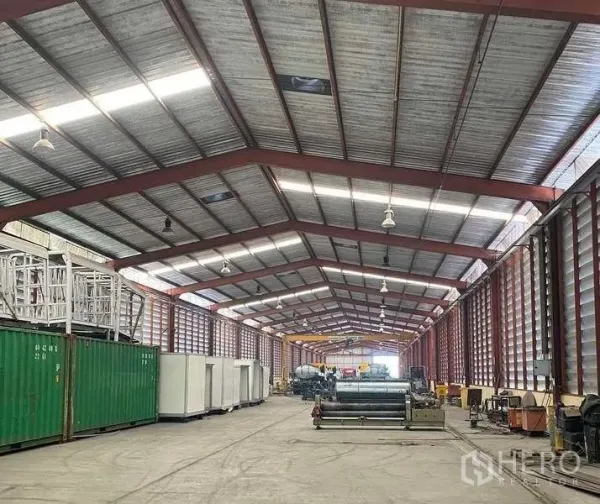 Factory for rent in Bang Kruai, Nonthaburi - Wide-span warehouse bay featuring metal beams, bright high-bay lighting, ventilated cladding and a clear central drive lane.