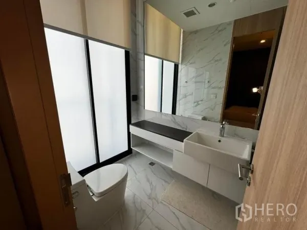 Condominium for rent in Watthana, Bangkok - Modern bathroom with frosted glass windows, marble tiles and floating vanity.