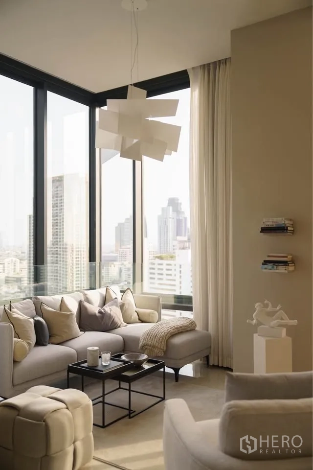 Condominium for rent in Bang Rak, Bangkok - Living room with floor-to-ceiling corner windows, sectional sofa, and skyline view.