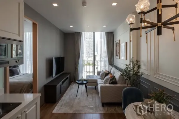 คอนโด ให้เช่าในWatthana, Bangkok - ห้องนั่งเล่นสว่างตกแต่งผนังบัว โซฟาและระเบียงชมวิวสกายไลน์กรุงเทพฯ