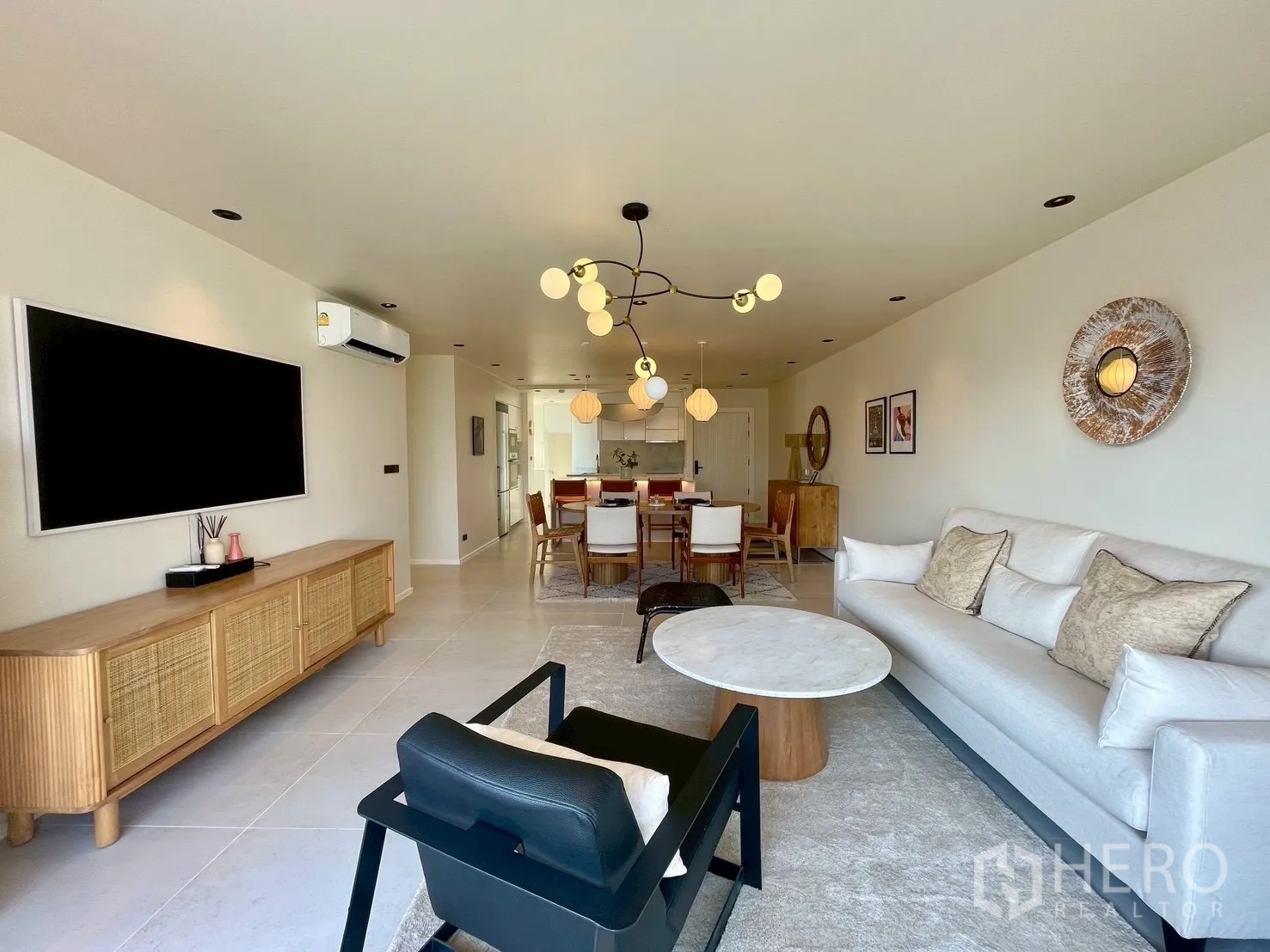 Condominium for sale in Watthana, Bangkok - Open-plan living and dining area with modern chandelier and large TV console.