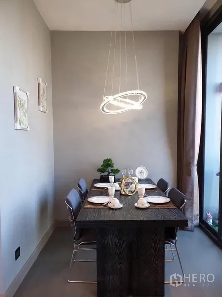 Condominium for rent in Huai Khwang, Bangkok - Cozy dining area for four under a contemporary ring pendant light beside a large window.
