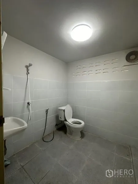 Warehouse for rent in Sai Noi, Nonthaburi - Clean restroom with toilet, basin and handheld shower inside the warehouse.