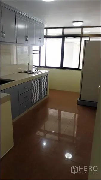 公寓 出租或出售在Khlong Toei, Bangkok - 独立厨房，灰色柜体，灶台、水槽、冰箱与大窗户采光。