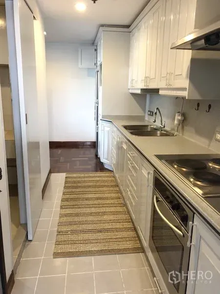 คอนโด ให้เช่าหรือขายในWatthana, Bangkok - มุมมองครัวอีกด้าน พร้อมเตาไฟฟ้า เครื่องดูดควัน และเคาน์เตอร์ยาว