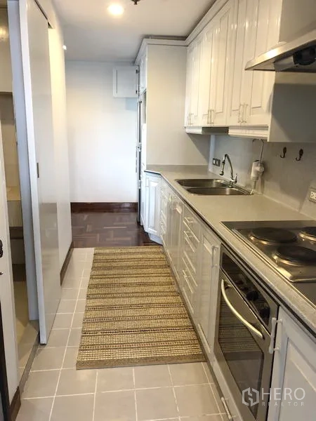 คอนโด ให้เช่าหรือขายในWatthana, Bangkok - มุมมองครัวอีกด้าน พร้อมเตาไฟฟ้า เครื่องดูดควัน และเคาน์เตอร์ยาว