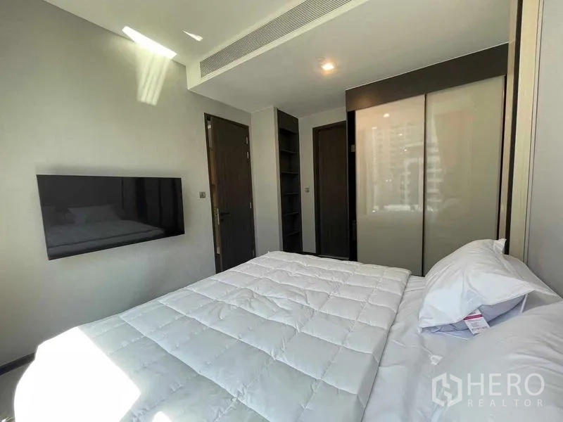 คอนโด ให้เช่า - มุมห้องนอนเห็นตู้เสื้อผ้า ประตู และทีวีติดผนัง