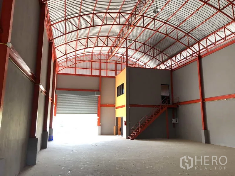 货栈 出租在Nonthaburi - 内部视角，设有卷闸装卸口与夹层办公室，并配钢制楼梯。