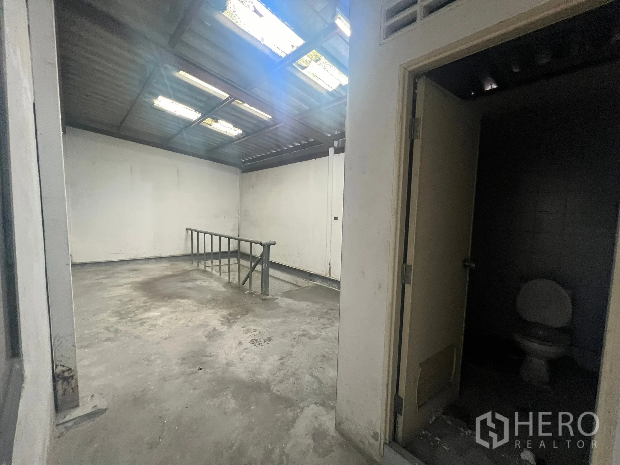 店屋 出租在Watthana, Bangkok - 后部混凝土区域，采光屋顶、金属栏杆与独立卫生间。