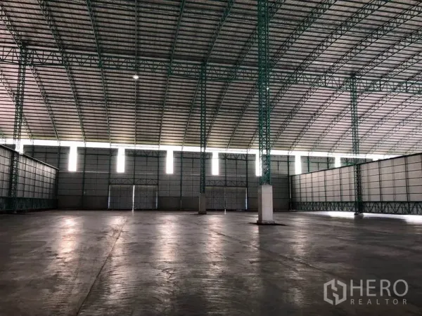 Warehouse for rent in Sai Noi, Nonthaburi - Vast hall featuring green steel columns, clerestory windows and polished concrete floor.