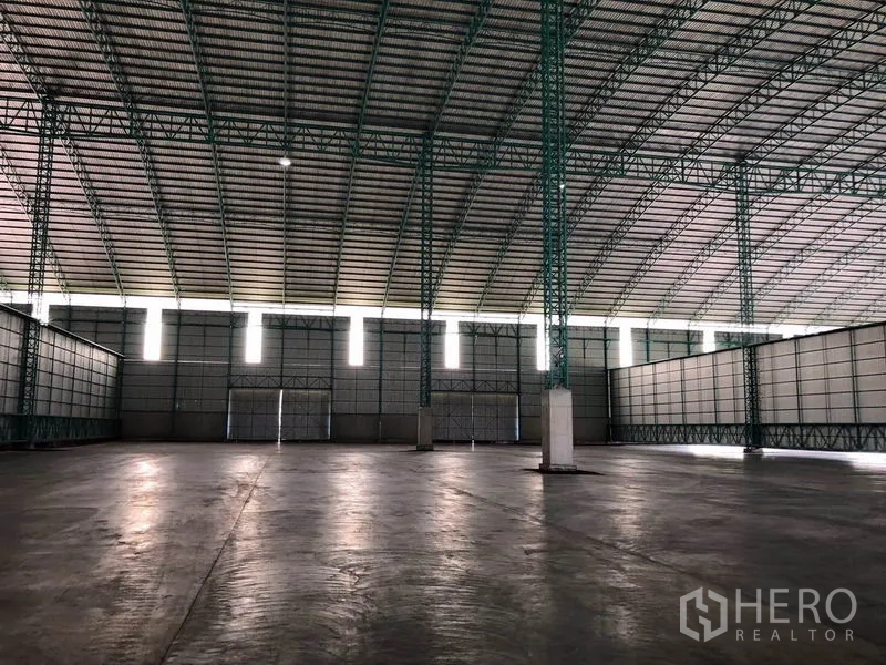 Warehouse for rent in Sai Noi, Nonthaburi - Vast hall featuring green steel columns, clerestory windows and polished concrete floor.