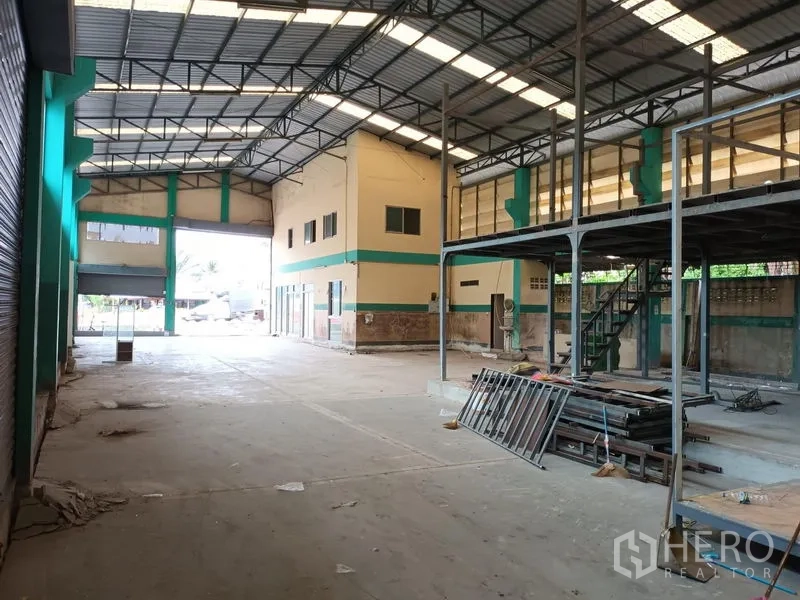 Warehouse for rent in Phasi Charoen, Bangkok - Large loading bay with mezzanine structure and concrete flooring.