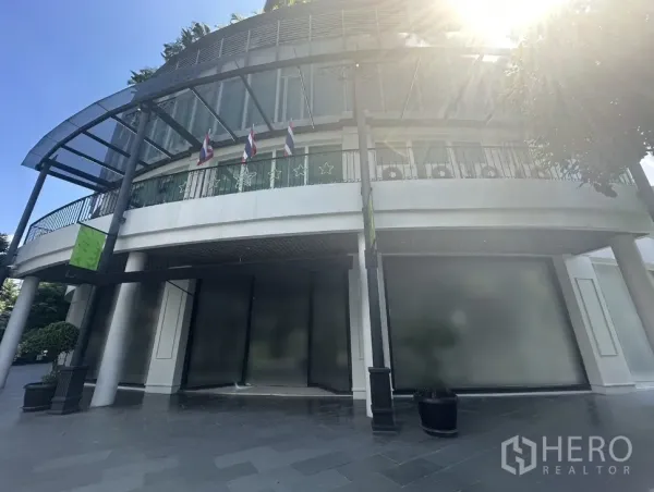 Office Space for rent in Khlong Toei, Bangkok - Curved modern building exterior with glass frontage, canopy and flags, ideal for an office entrance in Ekkamai.