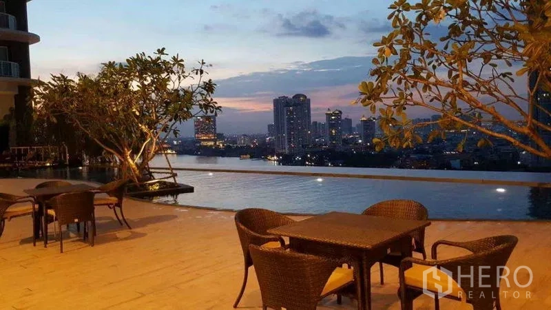 Condominium for rent in Bang Kho Laem, Bangkok - Sunset by the infinity pool with outdoor dining and skyline views.