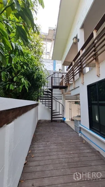 Detached House for rent in Saphan Sung, Bangkok - Side wooden deck with an exterior spiral staircase leading to the upper floor.