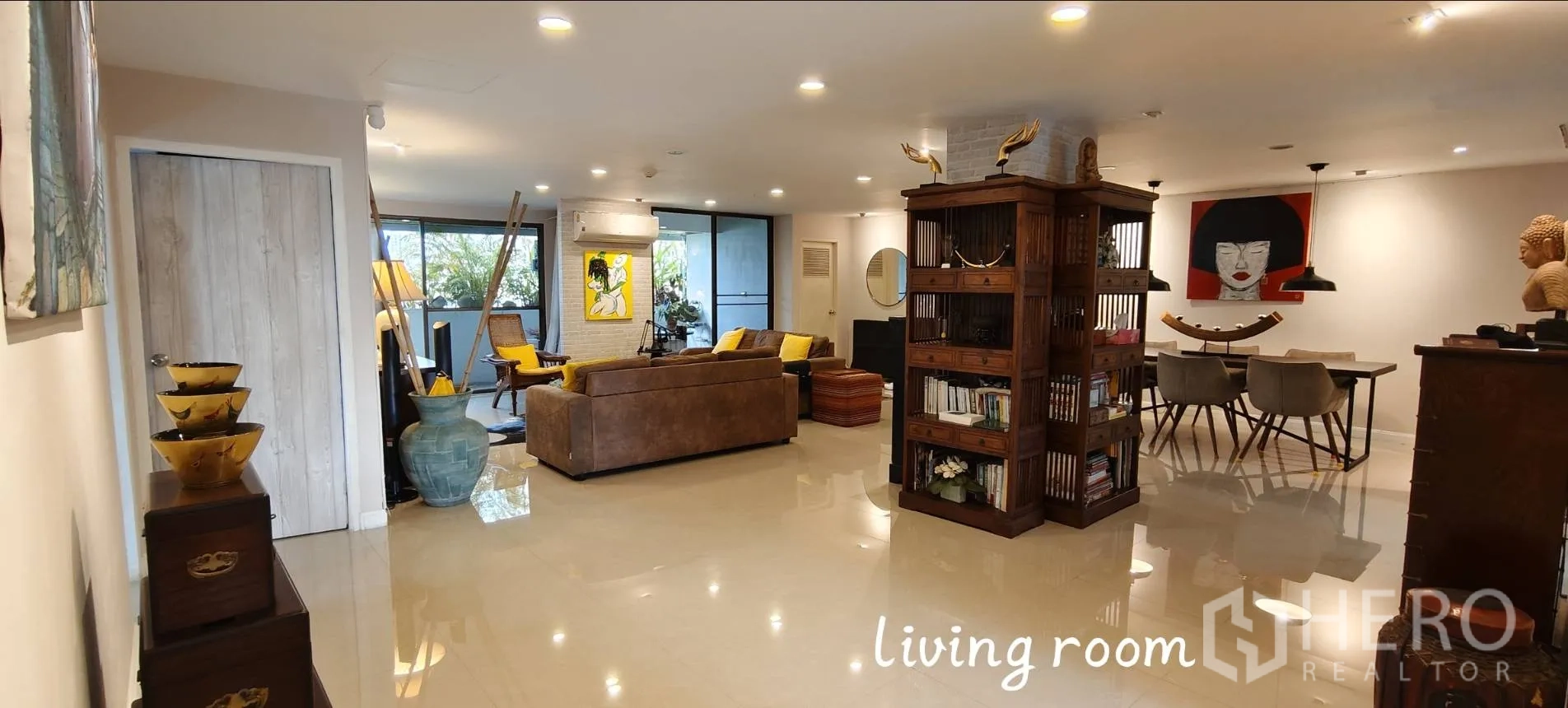 คอนโด for rent in Watthana, Bangkok - พื้นที่นั่งเล่นกว้างพร้อมชั้นหนังสือไม้ งานศิลป์ และทางออกสู่ระเบียง