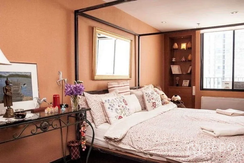 Condominium for rent in Watthana, Bangkok - Bedroom with canopy frame beside a large window, built-in shelving and city view.
