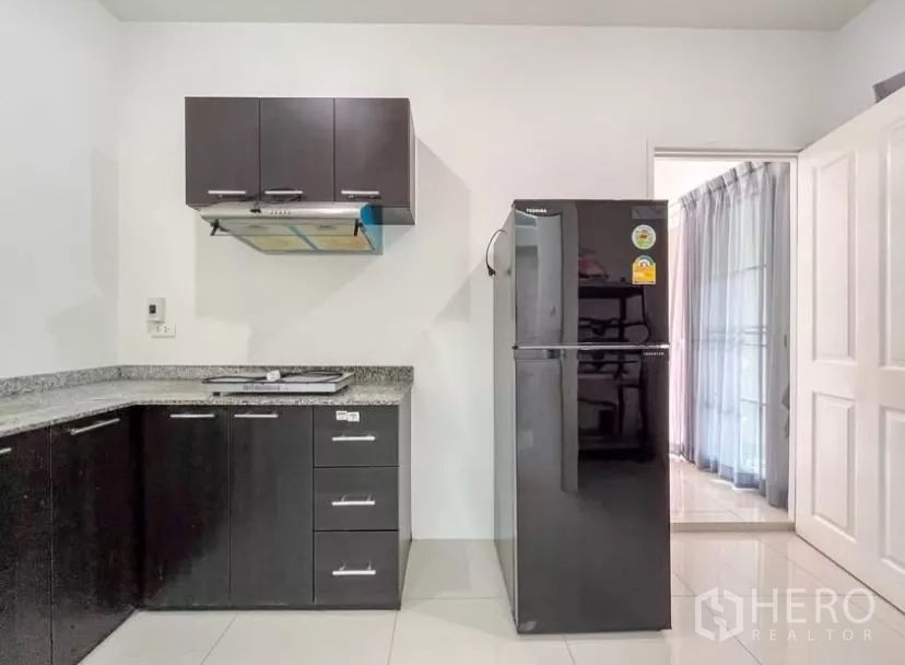 独立式住宅 出租在Chom Thong, Bangkok - L形厨房细节：吊柜、抽油烟机与双门冰箱。