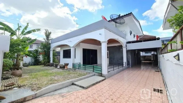 独立式住宅 出租在Lat Phrao, Bangkok - 拉抛区两层独栋住宅，拱形门廊、长铺砖车道与前花园，晴空下。