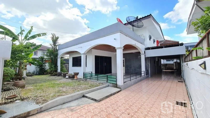 独立式住宅 出租在Lat Phrao, Bangkok - 拉抛区两层独栋住宅，拱形门廊、长铺砖车道与前花园，晴空下。