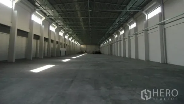 货栈 出租在Bang Sao Thong, Samut Prakan - 空置的通廊式仓库大厅，层高挑高，通风窗与混凝土地面。