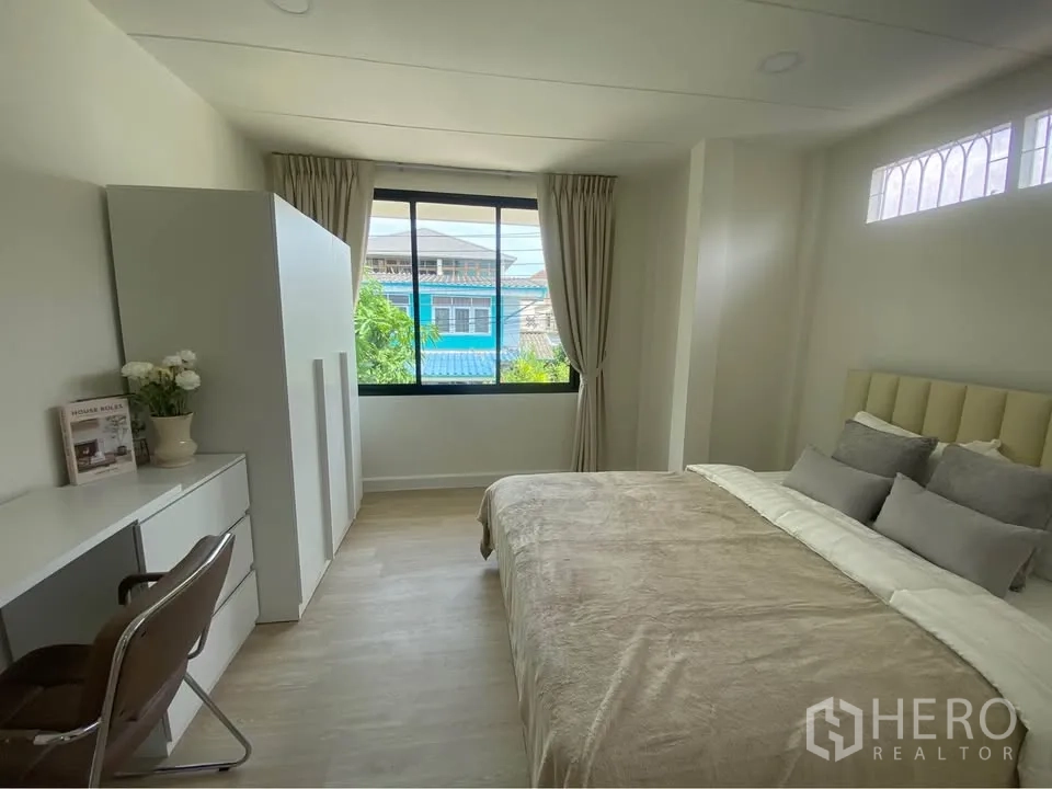 独栋房屋 for rent in Huai Khwang, Bangkok - 明亮卧室配大窗、书桌、衣柜与双人床，色调柔和。