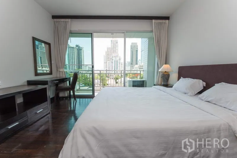 Apartment for rent in Sathon, Bangkok - Master bedroom with king bed, wood floors, balcony, and Bangkok skyline view.