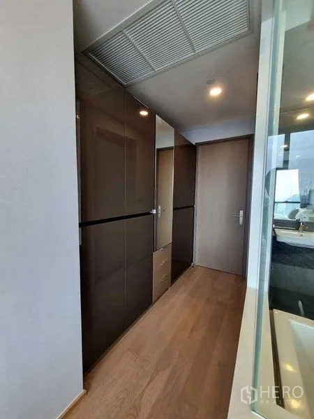 公寓 出租在Bang Rak, Bangkok - 过道设亮面衣柜，旁为玻璃墙浴室。