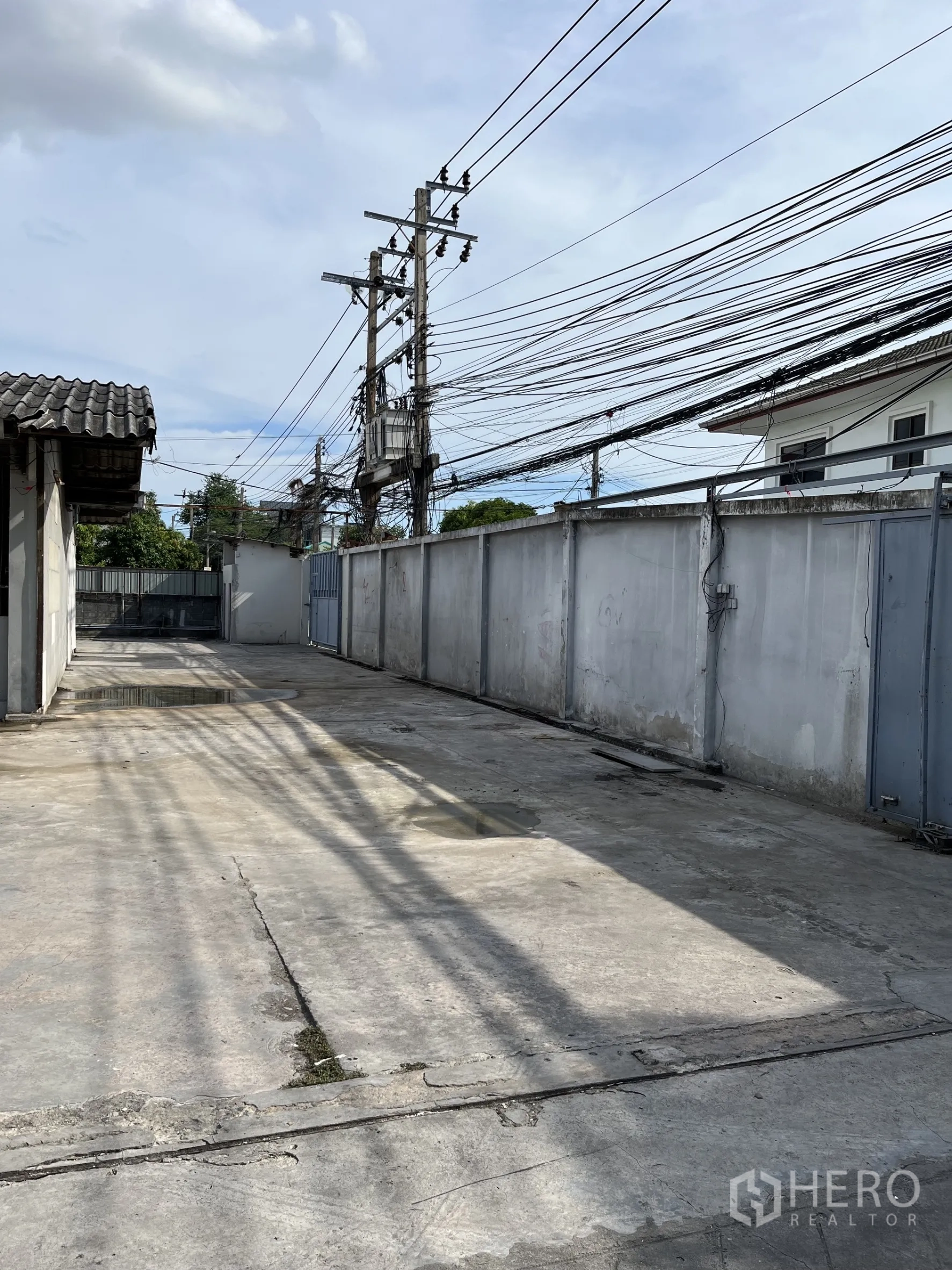 คลังสินค้า ให้เช่าในBangkok - ซอยทางข้างและลานคอนกรีตรอบรั้ว พร้อมเสาไฟและสายไฟ