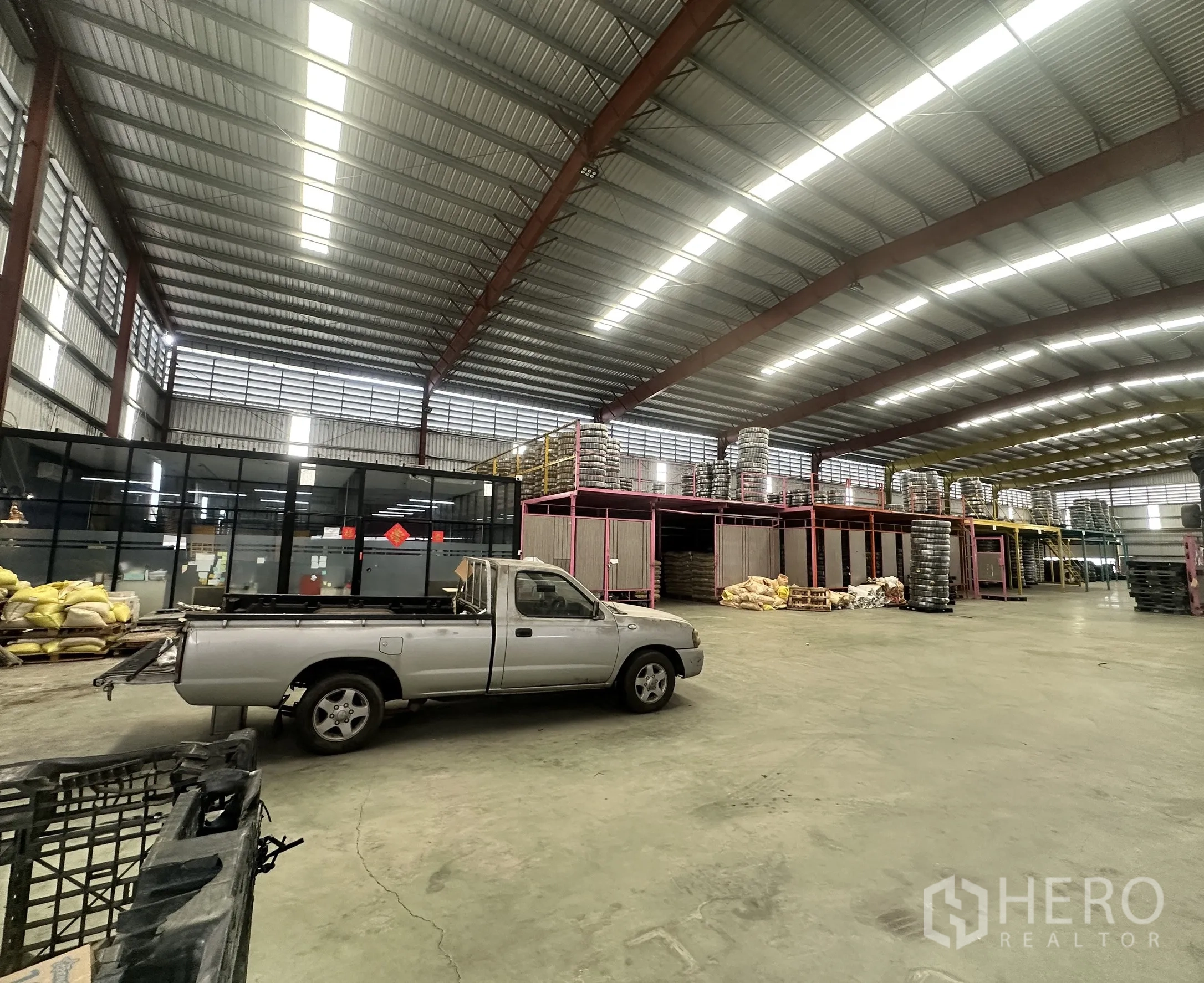 Warehouse for rent in Mueang Samut Prakan, Samut Prakan - Spacious warehouse interior with steel beams, concrete floor and glass-partitioned office.