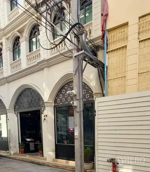 零售空间 出租在Watthana, Bangkok - 古典拱形立面的白色建筑，玻璃店面，临近澎蓬站的街景。