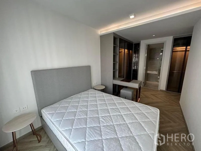 Condominium for rent in Watthana, Bangkok - Primary bedroom with upholstered bed, built-in shelving and access to an ensuite bathroom.
