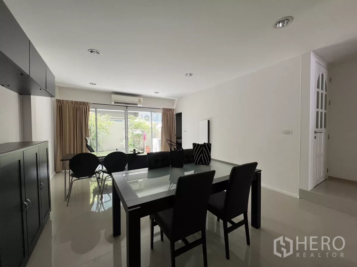 Townhouse for rent in Suan Luang, Bangkok - Dining area with large glass doors, white walls, and polished tile floors.