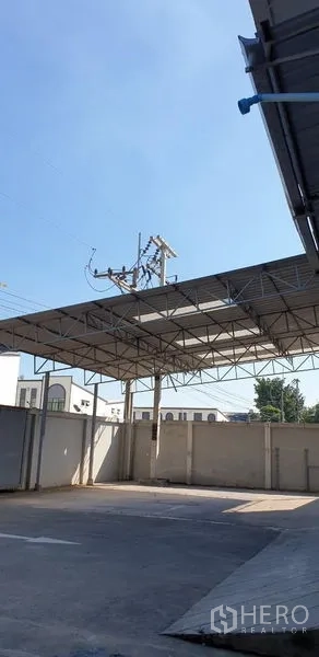 คลังสินค้า ให้เช่าในLam Luk Ka, Pathum Thani - โครงหลังคาเหล็กคลุมลานโล่ง เห็นท้องฟ้าและสายไฟด้านบน