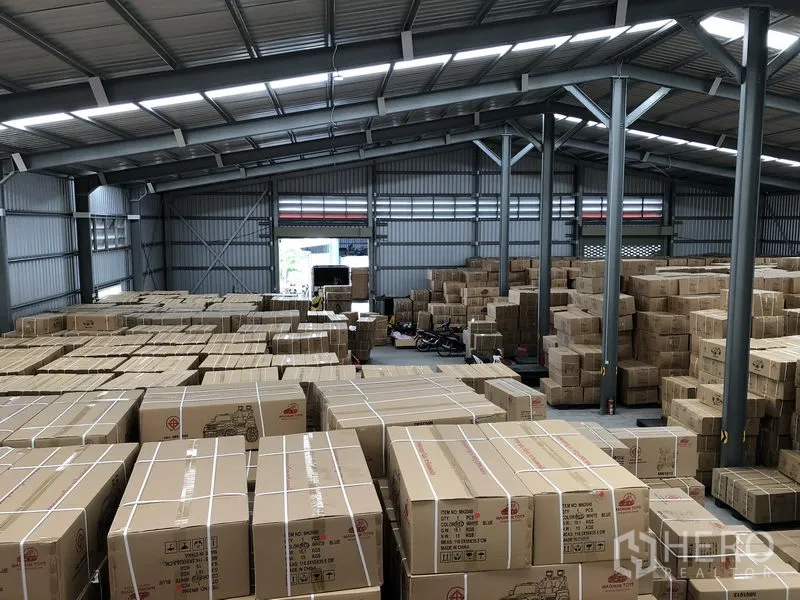 Warehouse for rent in Nonthaburi - Elevated view of warehouse storage area showing numerous packed cartons under a steel roof.