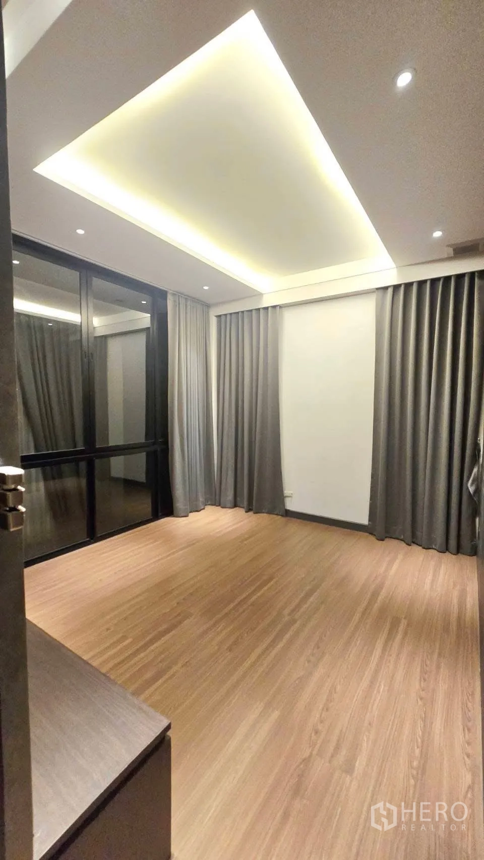 Detached House for rent in Prawet, Bangkok - Room with cove ceiling lighting, wood floors and full-length curtains by sliding doors.