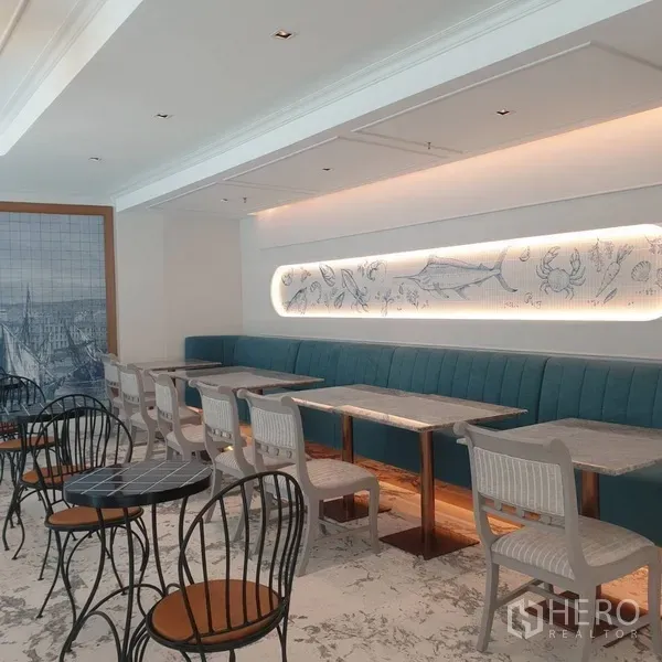 零售空间 出租在Khlong Toei, Bangkok - 沿灯带墙面的长排卡座，配多张咖啡桌与装饰壁画。