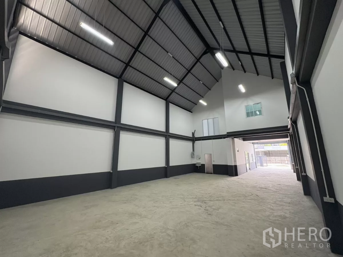 工厂 出租或出售在Bang Bua Thong, Nonthaburi - 纵深仓库通道朝向出入口，钢梁结构与LED照明。