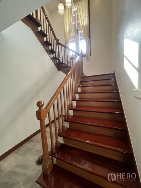 Detached House for rent in Bang Phli, Samut Prakan - Polished wooden staircase with banister leading to the upper floor and high window.