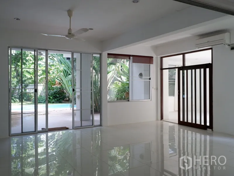 Detached House for rent in Khlong Toei, Bangkok - Living room with tiled floors, air conditioning and sliding doors to the patio and pool.