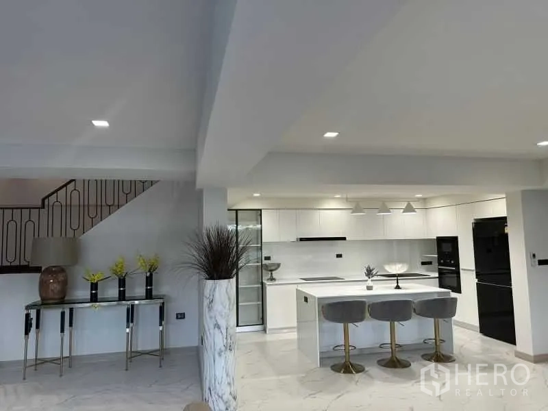 Detached House for rent in Suan Luang, Bangkok - Open-plan view of kitchen island with built-ins and black appliances.