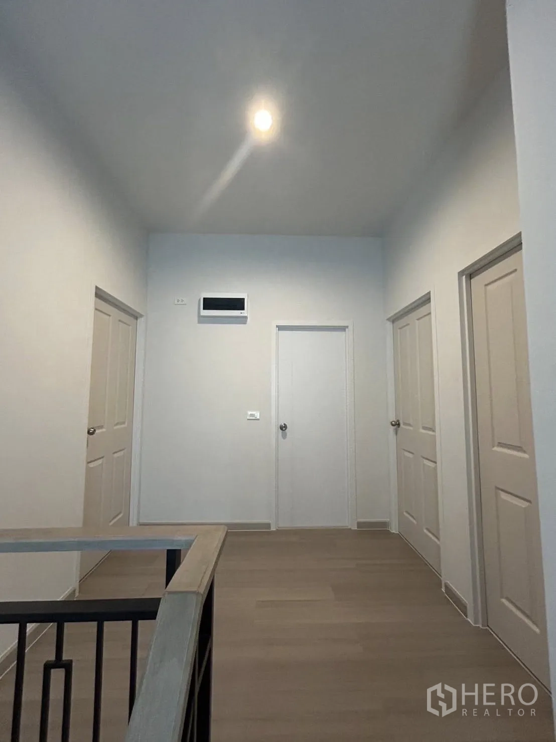 Detached House for rent in Khlong Sam Wa, Bangkok - Upper-floor landing with multiple bedroom doors and warm wood flooring.