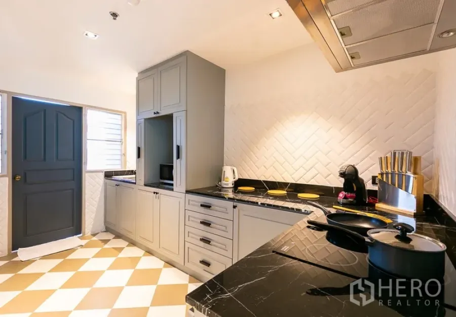 อพาร์ทเมนท์ ให้เช่าในKhlong Toei, Bangkok - ครัวแยกเคาน์เตอร์หินสีดำ ตู้สีเทา และผนังลายก้างปลา