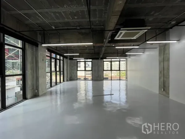 Office Space for rent in Khlong Toei, Bangkok - Corner office with wraparound windows, city outlooks and modern lighting in a loft-style setting.