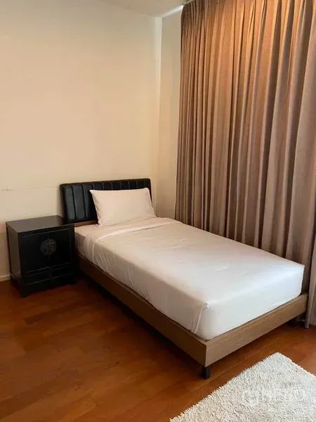 Condominium for rent in Watthana, Bangkok - Cozy single bedroom with wooden floor, single bed, bedside table, and full-length curtains.