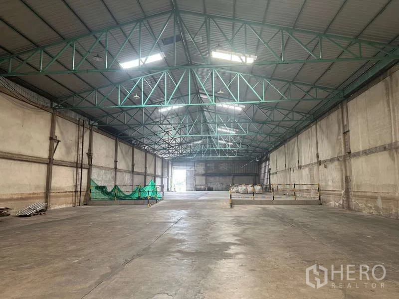 货栈 出租在Mueang Pathum Thani, Pathum Thani - 纵深仓内视角，天窗采光，尽头为大型出入口。