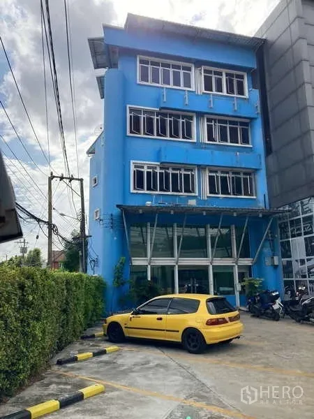 Shophouse for rent in Prawet, Bangkok - Frontage showing driveway, hedge and multiple on-site parking spaces at the building.
