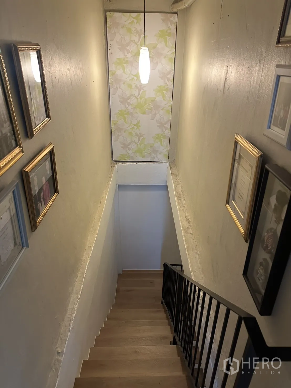 Shophouse for sale in Watthana, Bangkok - Narrow stairwell with pendant light and framed photos on the walls.
